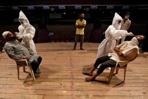 Healthcare workers in PPE collect swab samples from men during a rapid antigen testing campaign for COVID-19, at an auditorium turned into a testing centre in Ahmedabad, India, March 23, 2021. Reuters/Amit Dave