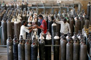 People carry oxygen cylinders after refilling them in a factory, amidst the spread of COVID-19 in Ahmedabad, April 25, 2021. Photo: Reuters/Amit Dave
